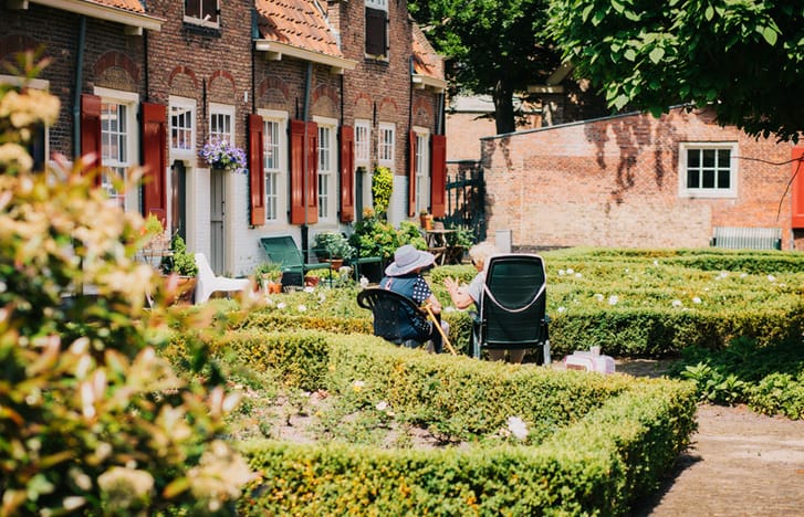 Two old ladies seated swap stories in the garden