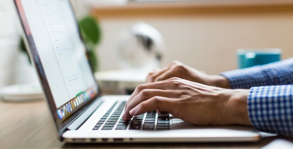 Mans hands working on laptop keyboard