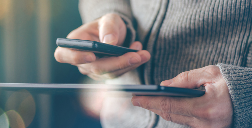 man holding mobile devices completing online transaction