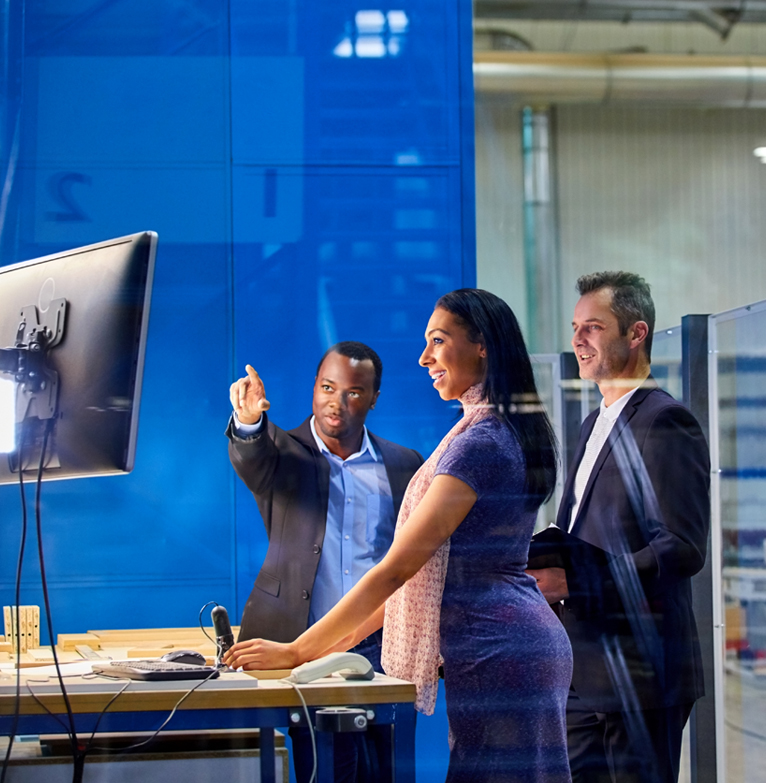 Group of people looking at a screen and talking in a warehouse environment