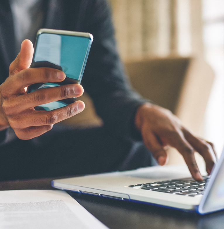 A client uses their laptop and phone simultaneously to manage their portfolio