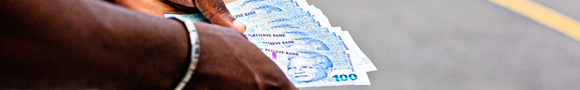 Hands holding South African Rand notes