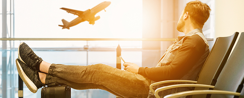 Male waiting at airport watching a plane take-off