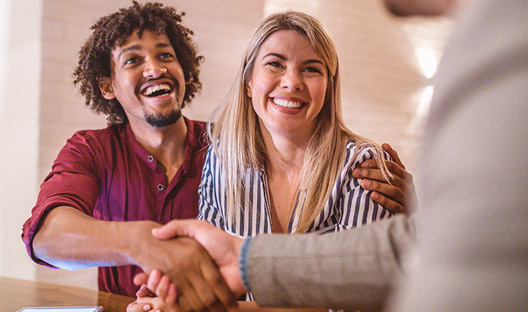 Couple shaking hands with agent after agreeing to buy home