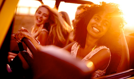 Female friends laughing in the car at sunset