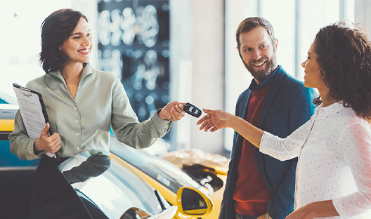 Female receiving the key to her brand new car