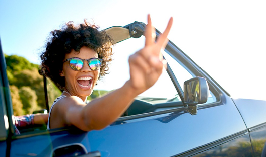 Happy female with peace sign driving in her car