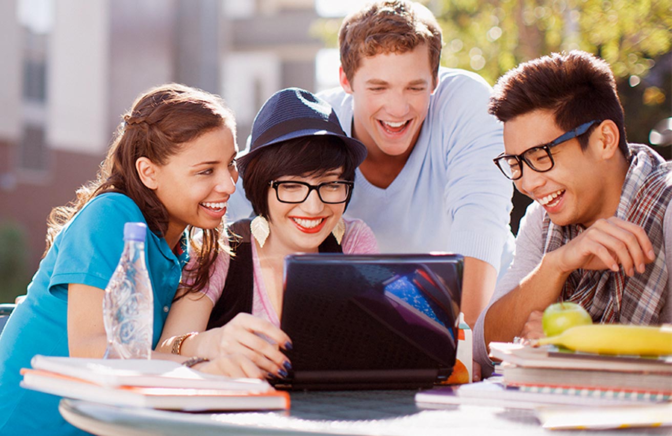 Group of students huddled around a laptop outside