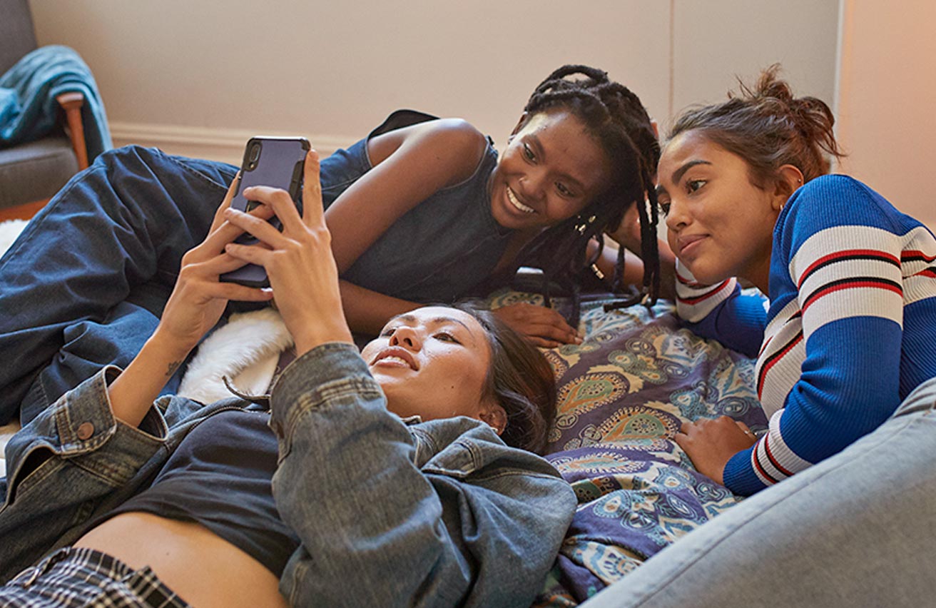 Young females checking social media on mobile phone together