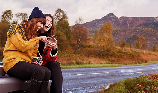 Couple traveling sitting on boot of car