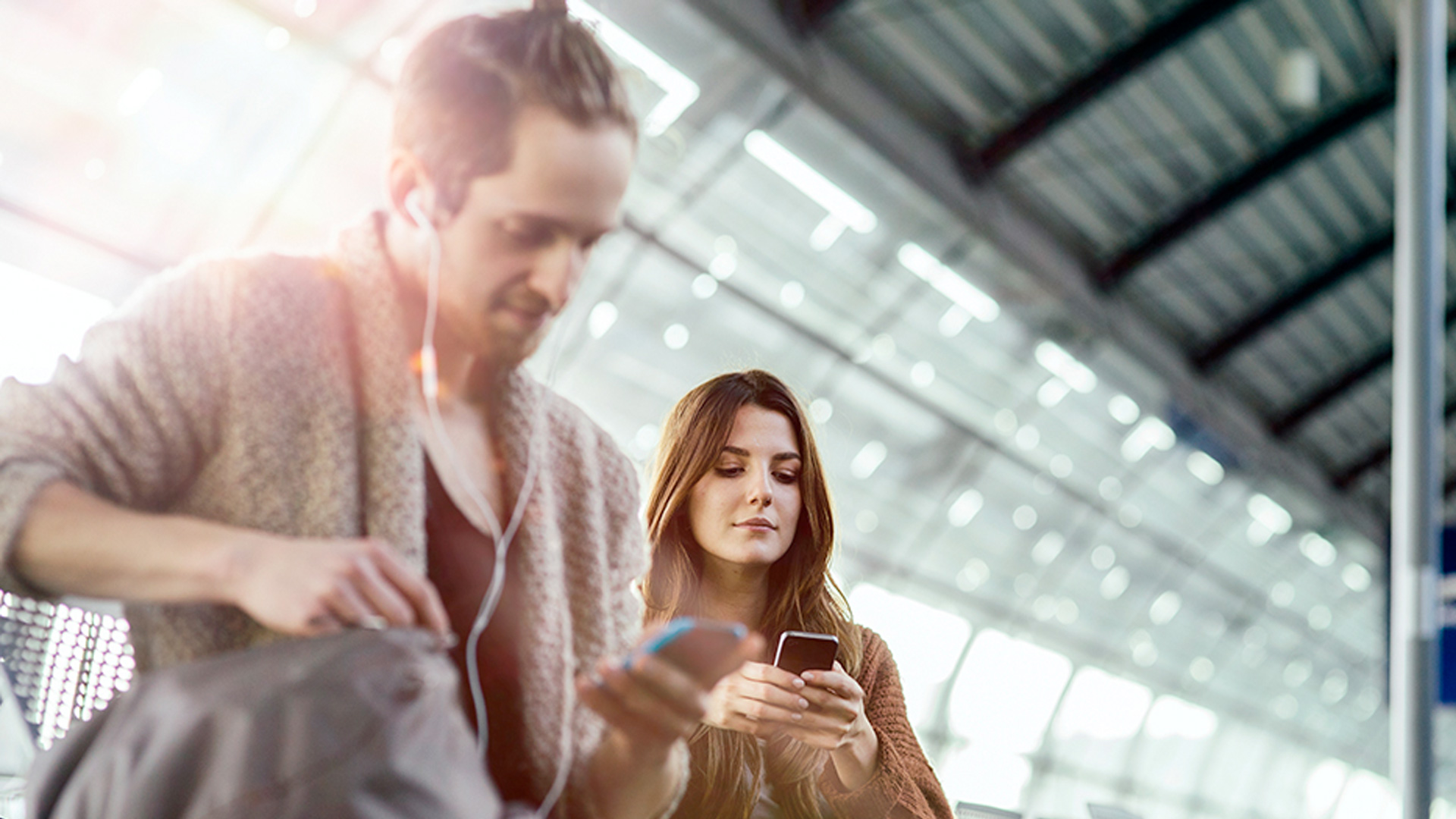 People checking their mobile phones while waiting for a train