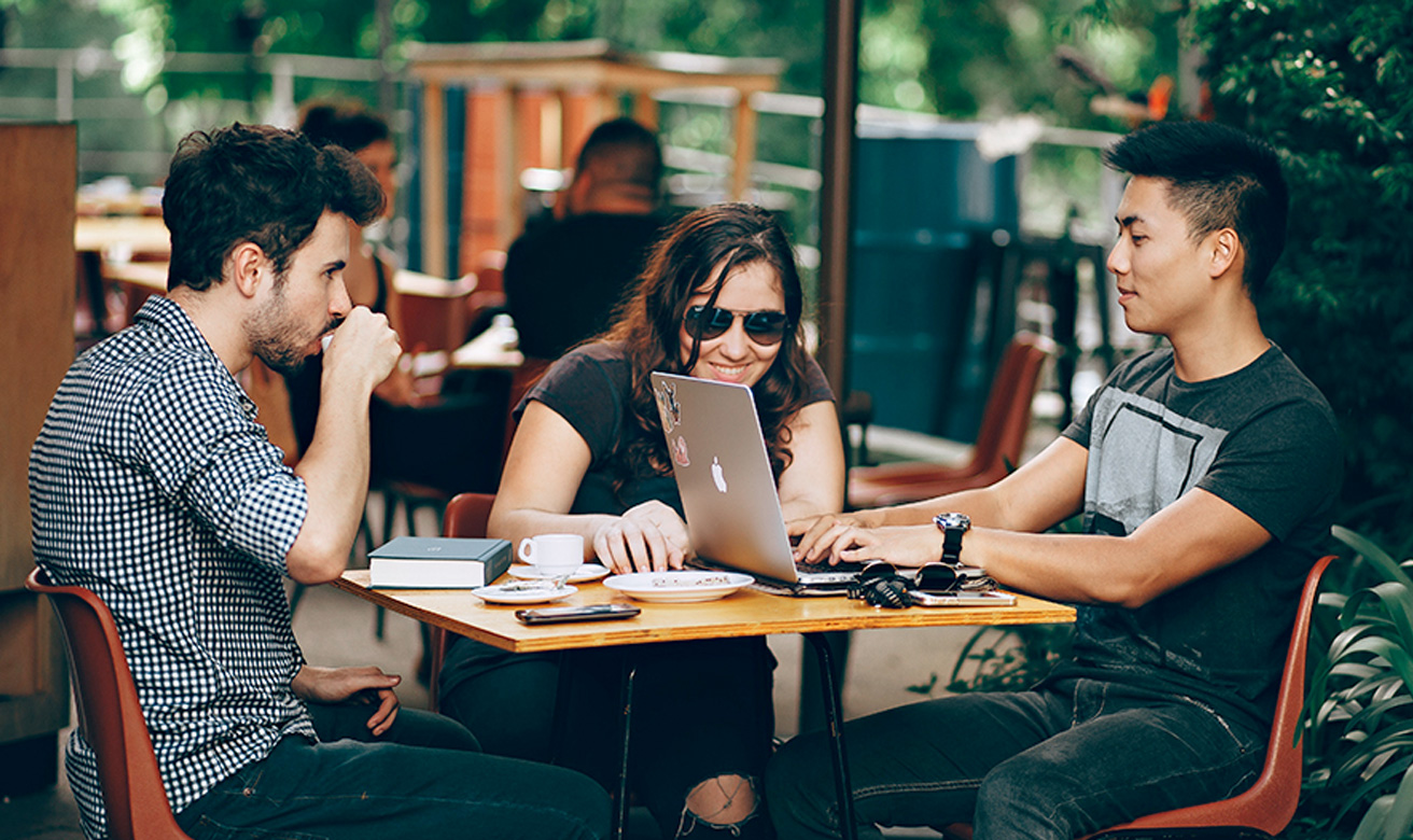 Young professionals looking at laptop outside coffee shop