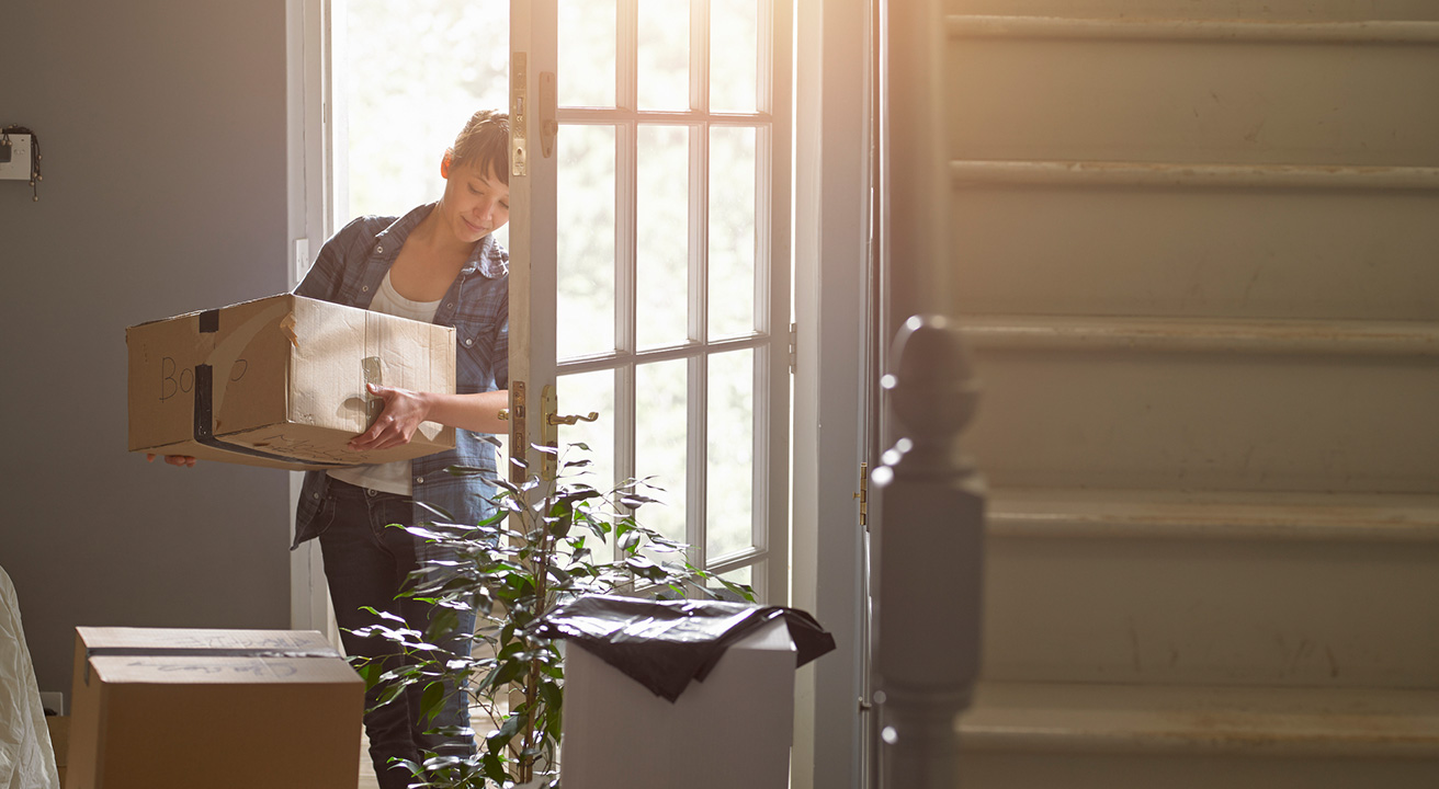 Woman carrying box into house