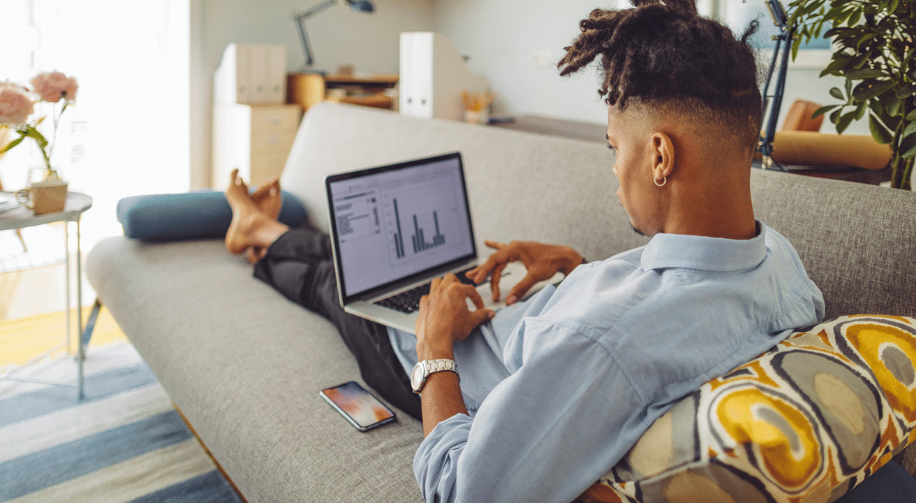 Man sitting on couch using laptop