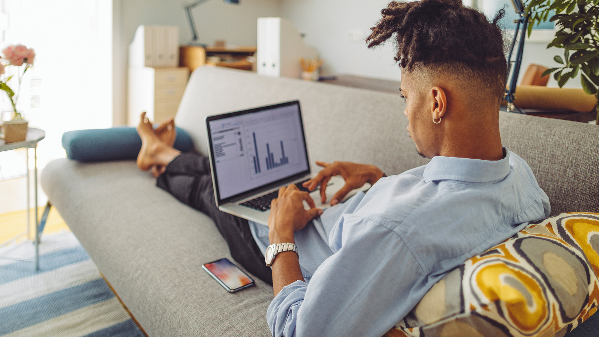 Man working on a laptop while laying on a couch