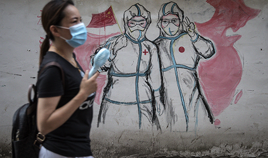 Chinese women infront of Covid-19 mural