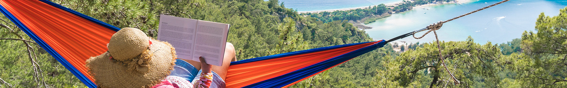 Woman reading book in a hammock view view of coastline