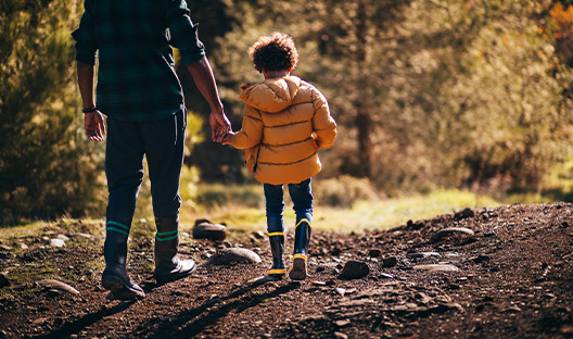 Dad holding son's hand while walking through woods