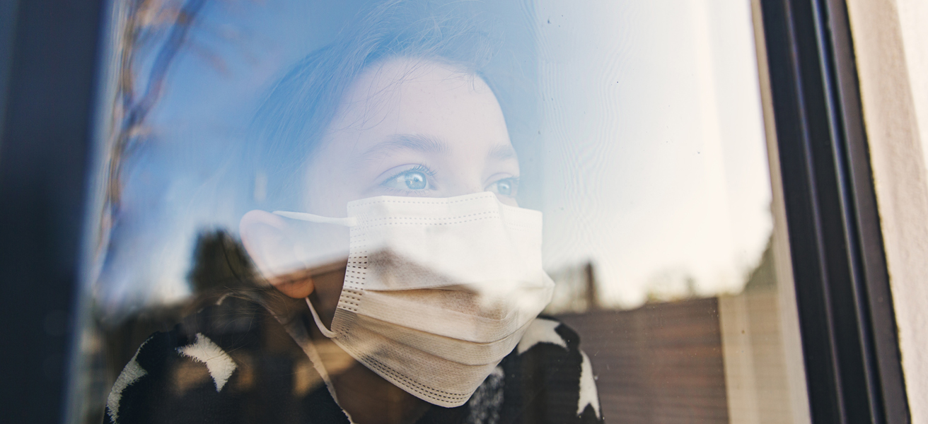 Child wearing a mask staring out the window