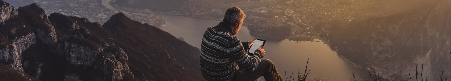 Man reading tablet on a mountain