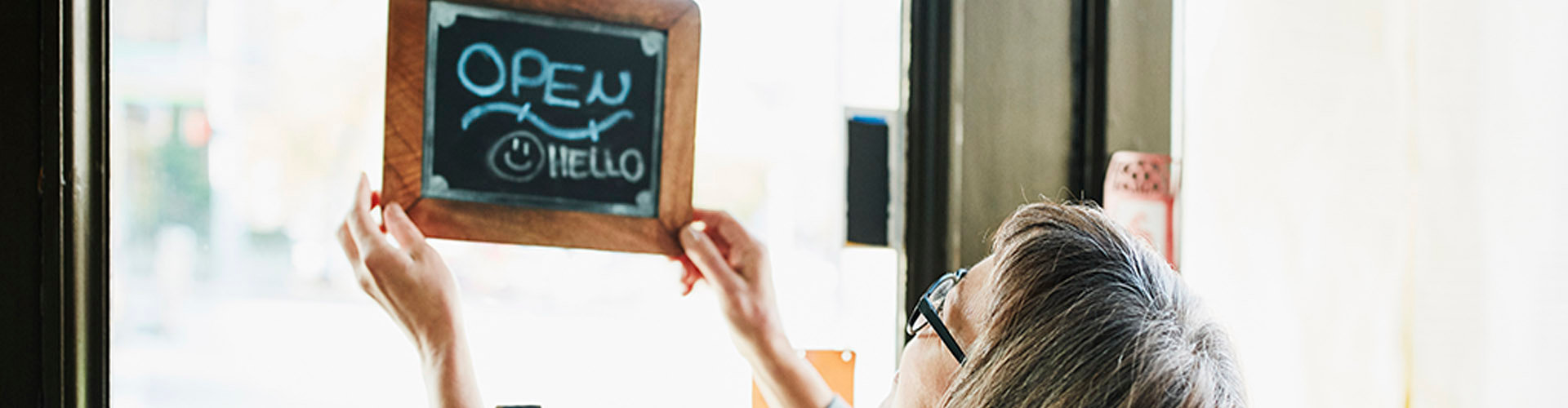 Women turning an open-for-business sign