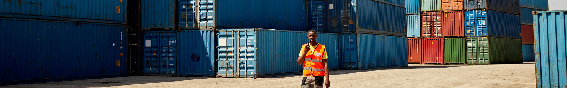 Man walking amongst shipping containers
