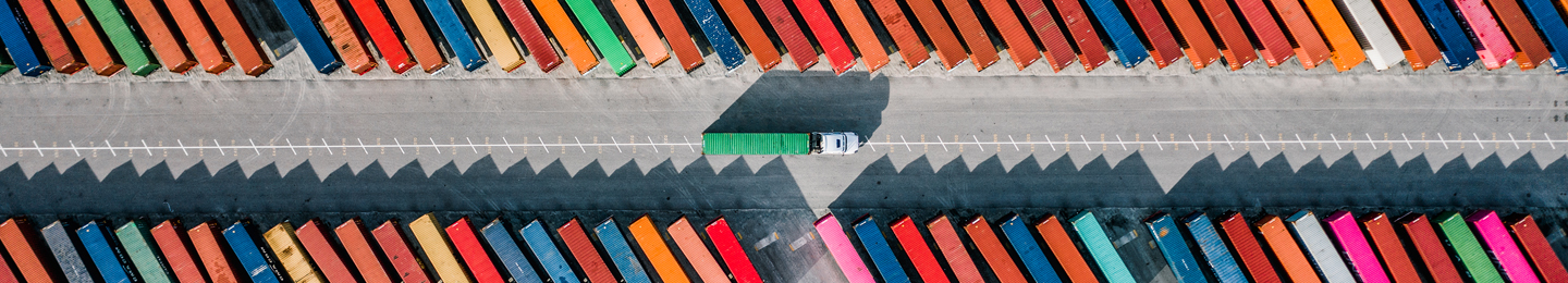 Supply chain: Truck driving between rows of shipping containers