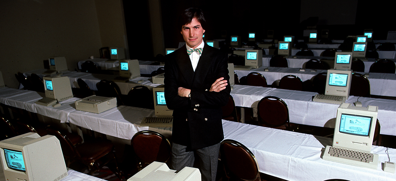 A young Steve Jobs surrounded by computers