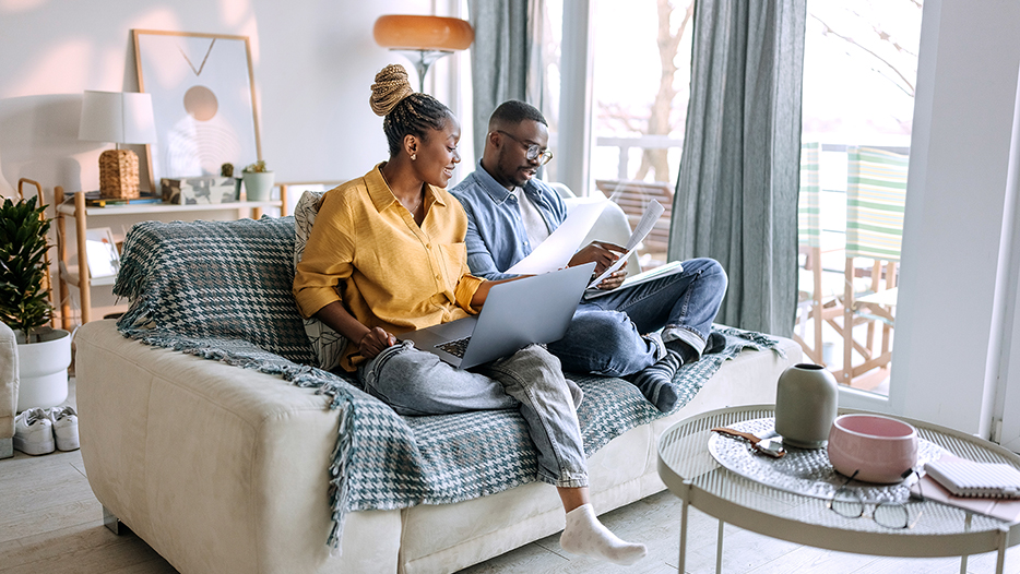 Couple looking through papers and a laptop on a couch
