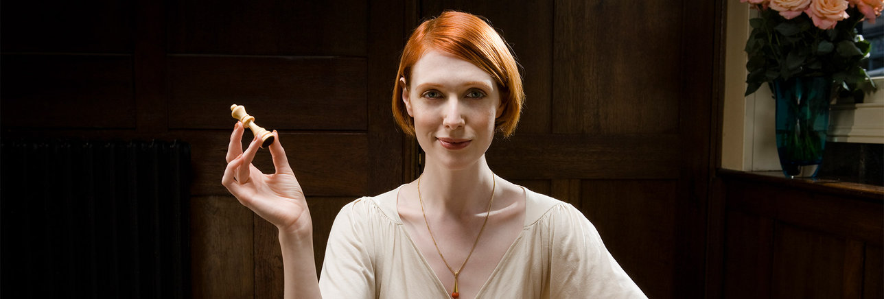 Female holding a queen chess piece