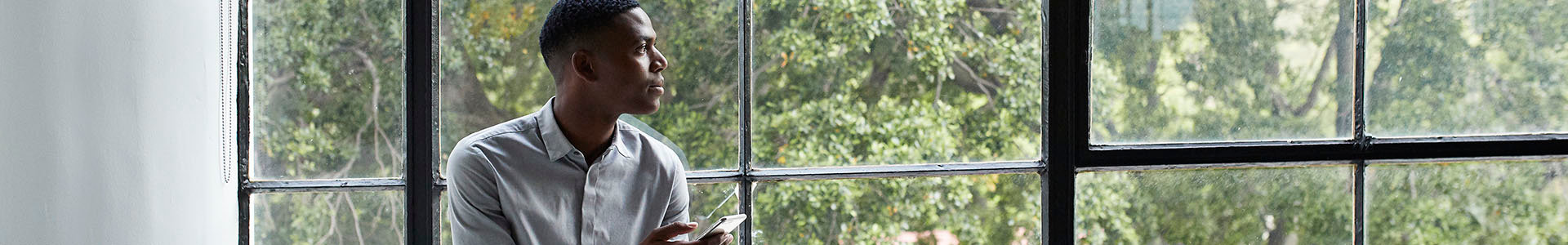 Man with phone staring out of window