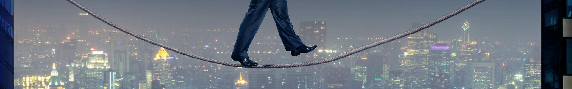 Businessman walking a tight rope over a city