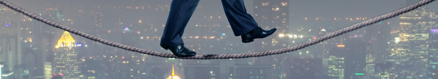 Businessman walking a tight rope over a city