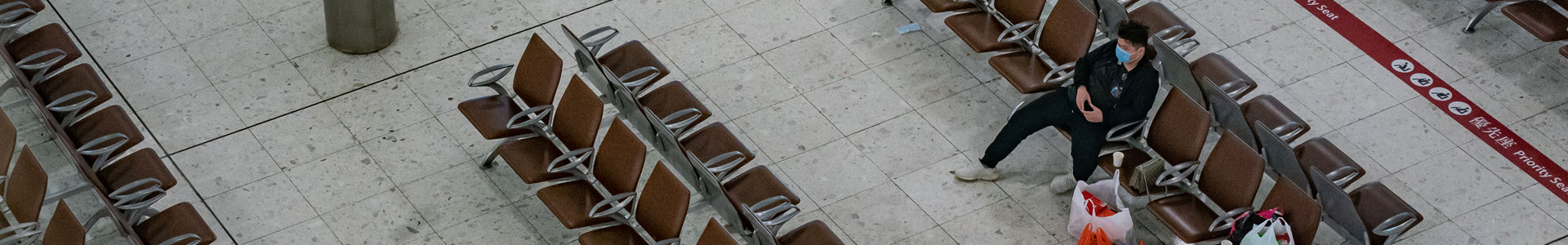 Lone man wearing face mask, sitting in empty airport terminal