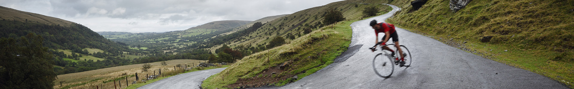 Cyclist going down hillside road
