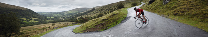 Cyclist going down hillside road