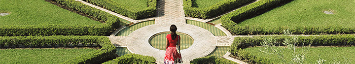 Female walking towards multiple path options in a garden