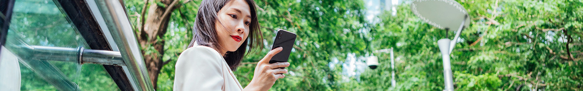 Asian woman looking at her phone in a park