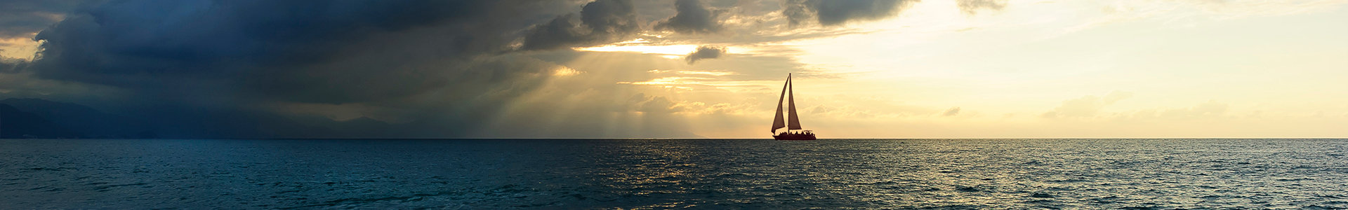 A yacht on a calm sea heads towards a big dark cloud on the horizon