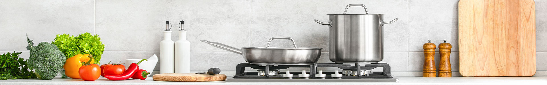 Kitchen worktop with pans on a stove, with vegtables to the side