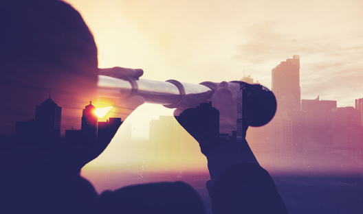 Person looking through a telescope at sunset