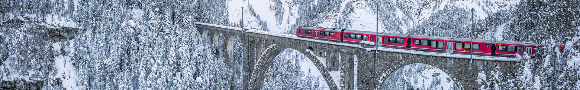 Red train crossing snowy bridge in Davos, Switzerland