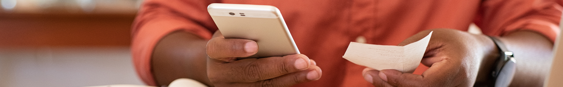 Male checking mobile phone with receipt in the other hand