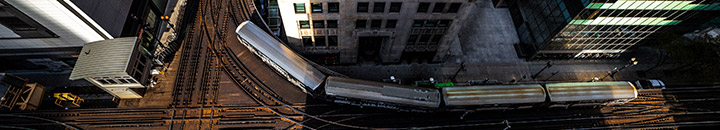 Train turning around a sharp corner in the track which is working around a building
