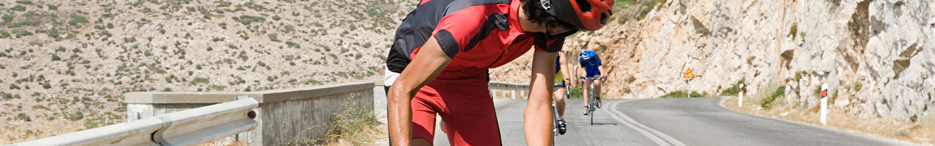 A man on a bycycle with 2 men closing the gap behind