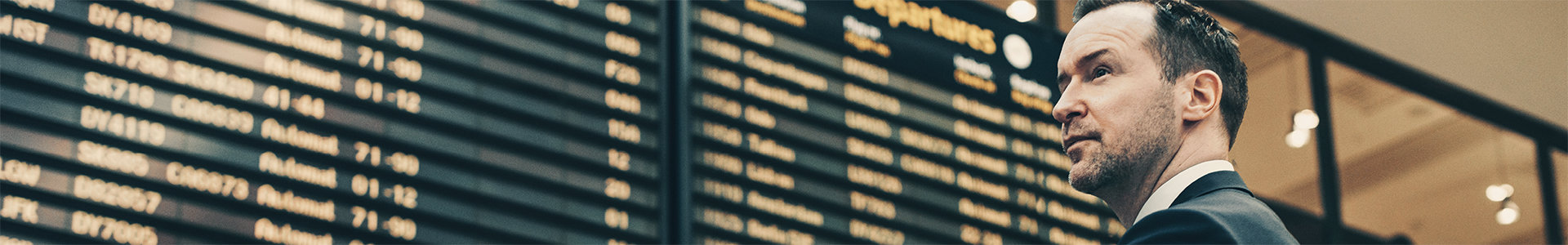 Man at airport looking at departure boards