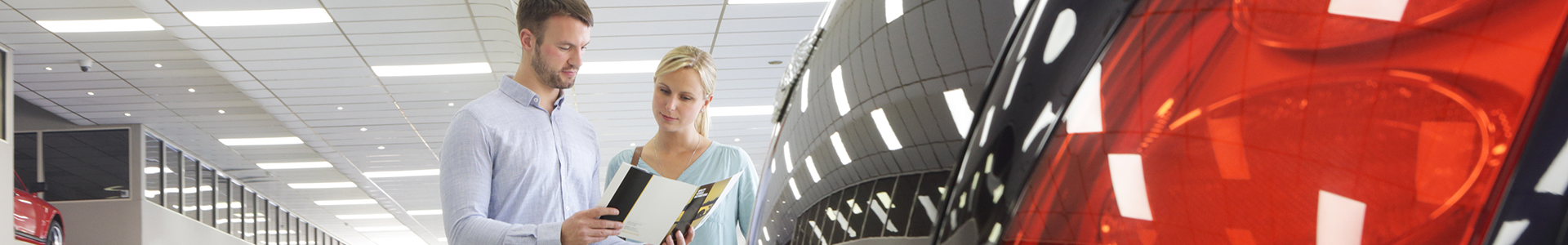 Couple reading a car brochure in a dealership