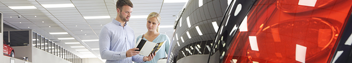 Couple reading a car brochure in a dealership