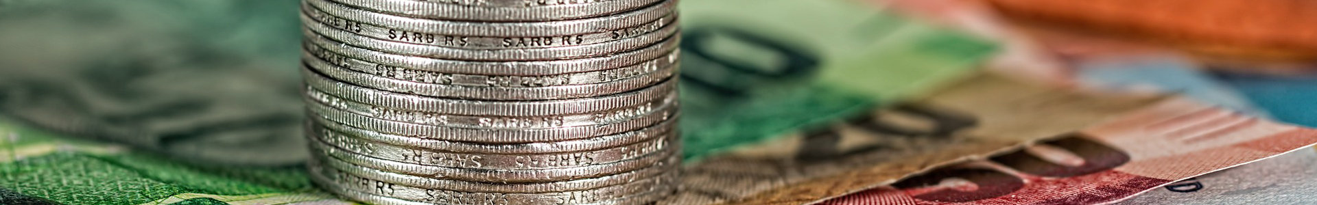 South African rand coins stacked on top of rands notes