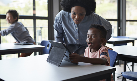 Teacher teaching a young boy on a laptop